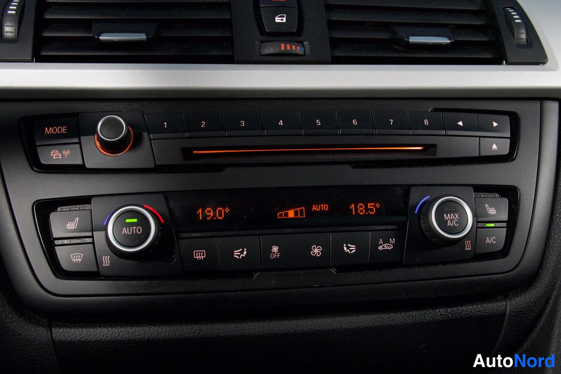 Yksityiskohta: Keskiöinti­paneeli: automaattinen kaksivöyhye-ilmastointi, näytössä 19,0° ja 18,5°, AUTO- ja MAX A/C -painikkeet, radion numeronäppäimet 1–8.