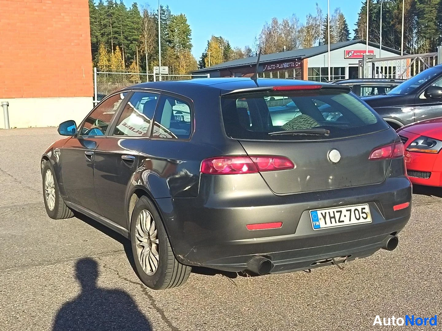 Takaviisto: Harmaan Alfa Romeo 159 Sportwagon -farmarin takapuoli ja vasen sivu, rekisterikilpi, auton alla varjo.