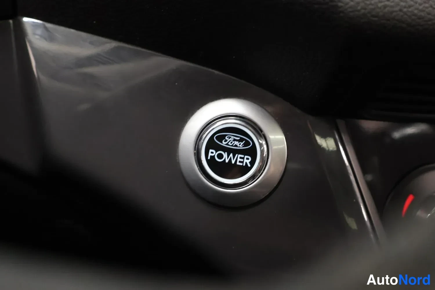 Yksityiskohta: Lähikuva virtaviivaisesta Ford-tuotesymbolista: nappi, jossa lukee 'Ford POWER'.