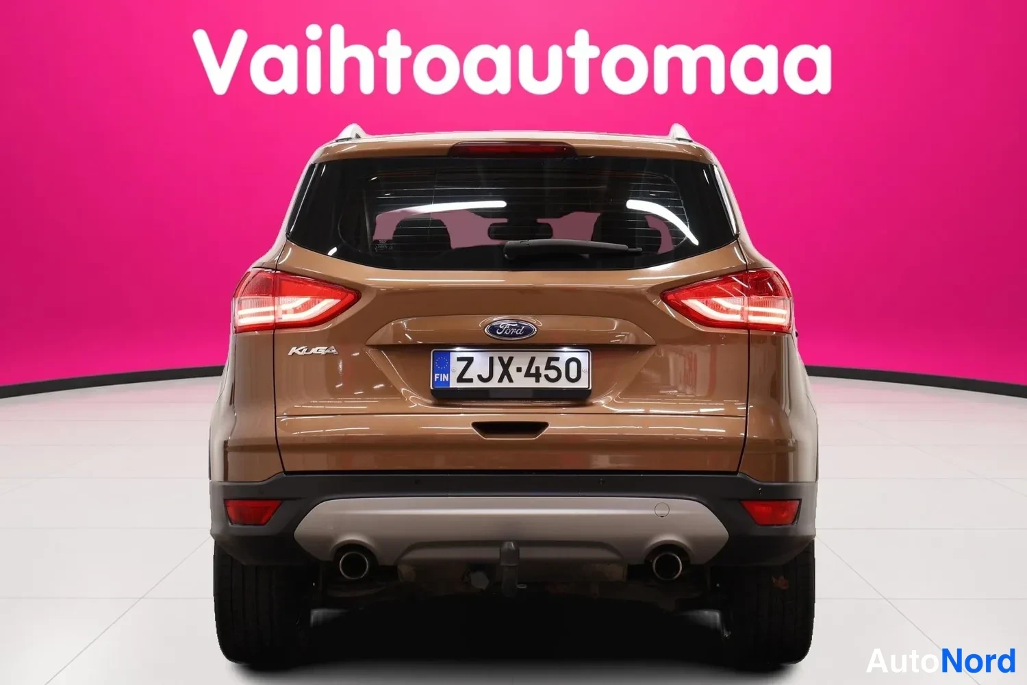 Takaa: Ford Kuga takaa päin kuvattuna, ruskea koriväri, rekisteritunnus, kattokaiteet ja vetokoukku näkyvät.