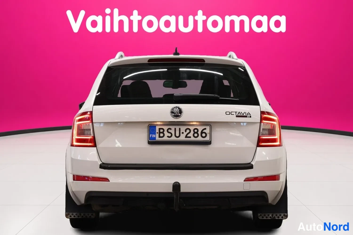 Takaa: Valkoisen Skoda Octavia Combi -farmariauto takaa kuvattuna, rekisterikilpi, jäähdytinverkko ja takavalot näkyvät.