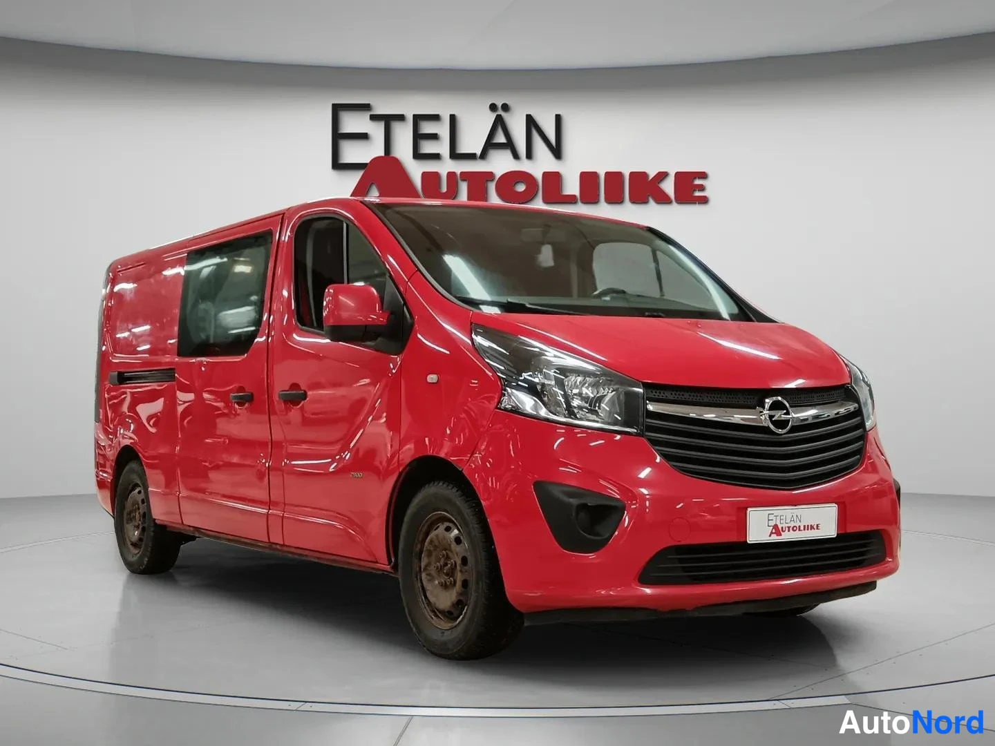Etuviisto, nokka oikealle: Punainen Opel Vivaro -pakettiauto etuviistosta oikealta kuvattuna studiosalissa.