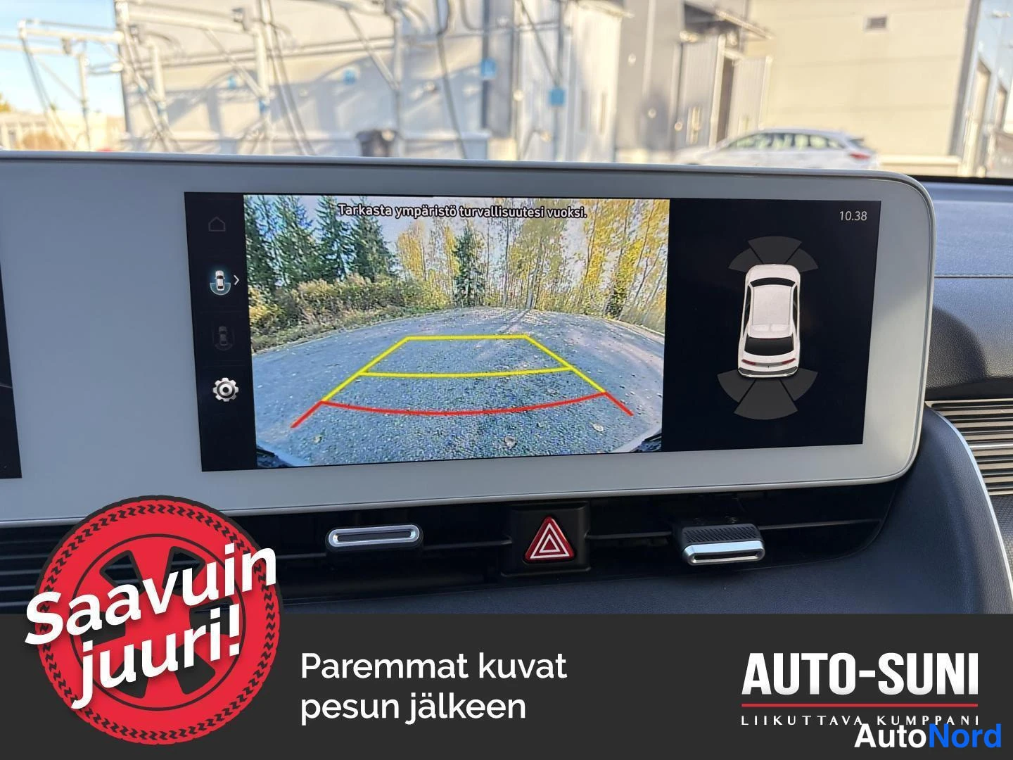 Yksityiskohta: Infotainment-näytöllä peruutuskameran kuva opastaviin viivoihin ja ympärivuoro-kameran ajoneuvonäkymä.