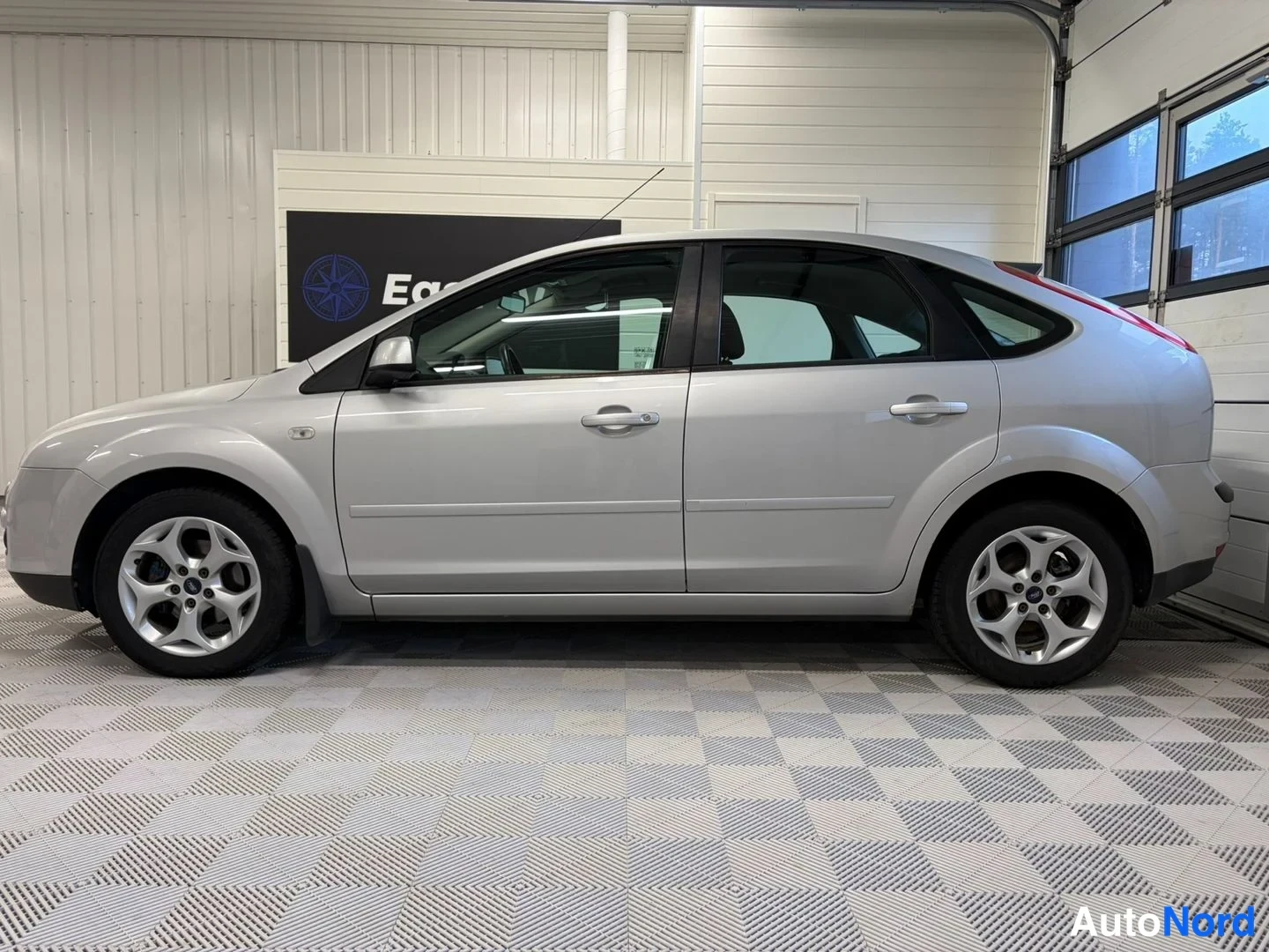 Sivulta: Hopeanvärinen Ford Focus sivulta, viistoperäinen kori ja hopeat renkaat näkyvät.