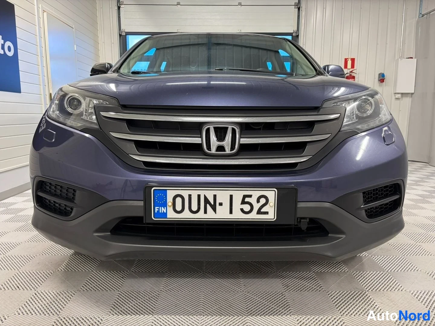 Edestä: Honda CR-V:n keulakuva suoraan edestä, ympyrävalot ja etupuskuri näkyvät, rekisterikilpi.