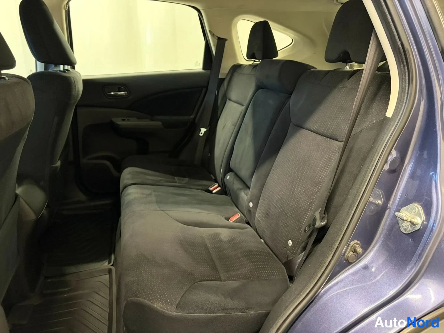 Sivulta: Honda CR-V:n takaistuin mustaa kangasta, takiovi auki.
