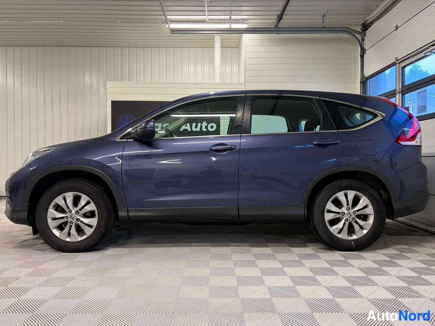 Etuviisto, nokka vasemmalle: Honda CR-V:n kylki ja etunurkka vasemmalta kuvattuna; tummansininen koripanelisto, hopeat kevytmetallivanteet.