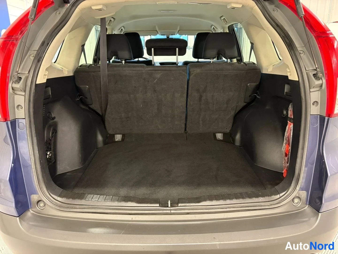 Takaa: Honda CR-V:n avattu tavaratila, takaselkänojat pystyssä, tumma matto.