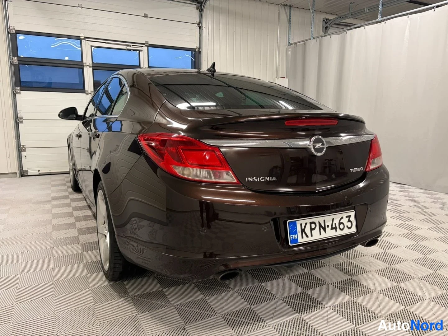 Takaviisto: Opel Insignian takakulma hallissa, takavalot, OPC-line -tunnus ja rekisterikilpi näkyvissä.