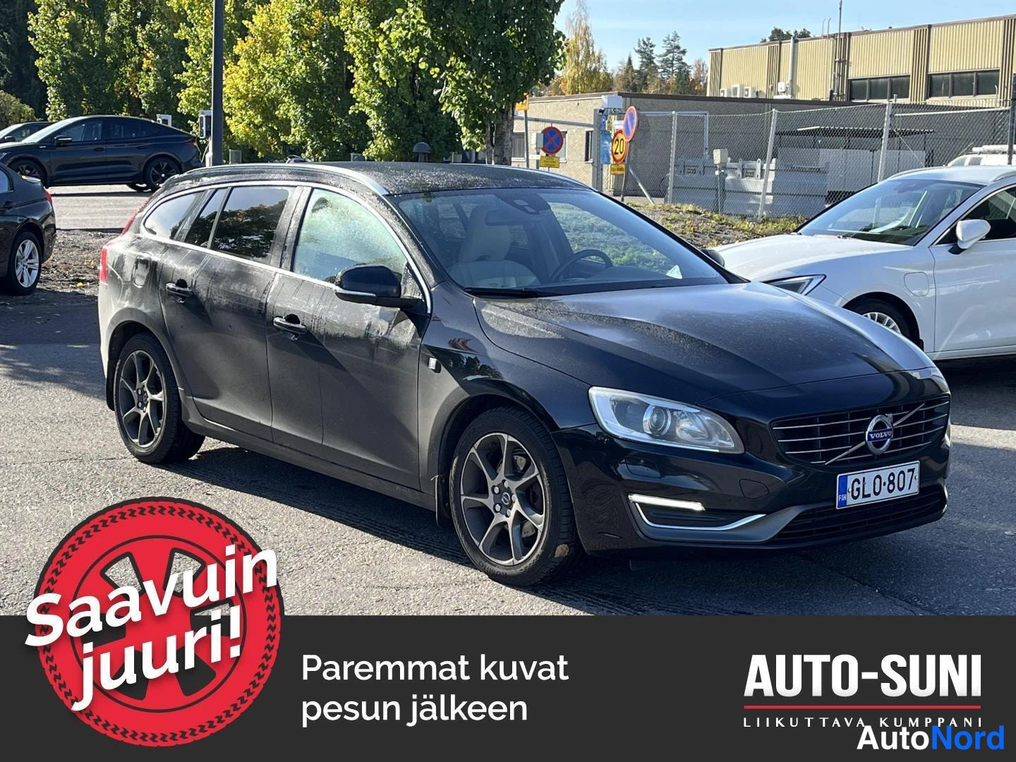 Etuviisto, nokka oikealle: Musta farmariauto kolmesti-neljännesnäkymässä edestä oikealta, rekisterikilpi, parkkipaikalla muiden autojen seassa.