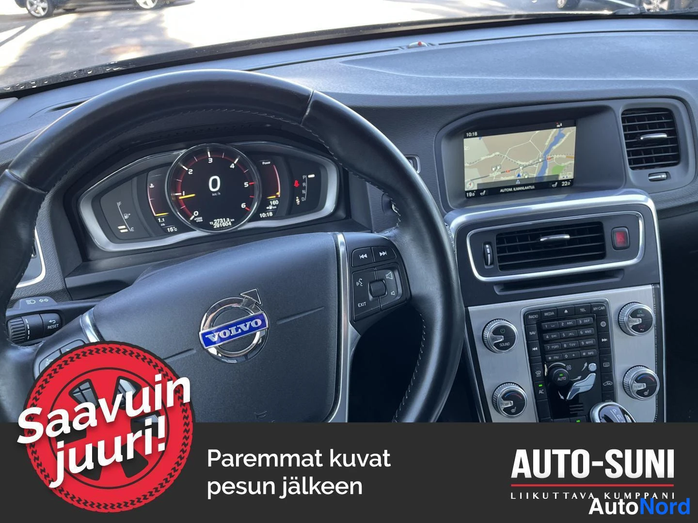 Sivulta: Näkymä ohjaamosta: Volvo-merkillinen ohjauspyörä, mittaristo ja karttaa näyttävä näyttö keskiövelteessä.