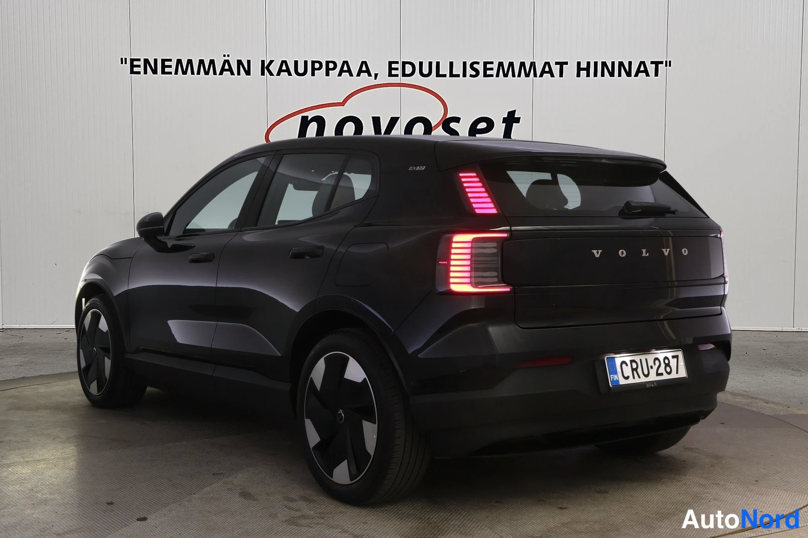 Takaviisto: Mustan Volvo EX30:n takakulmanäkymä, päälle sytytetyt takavalot ja rekisteritunnus.