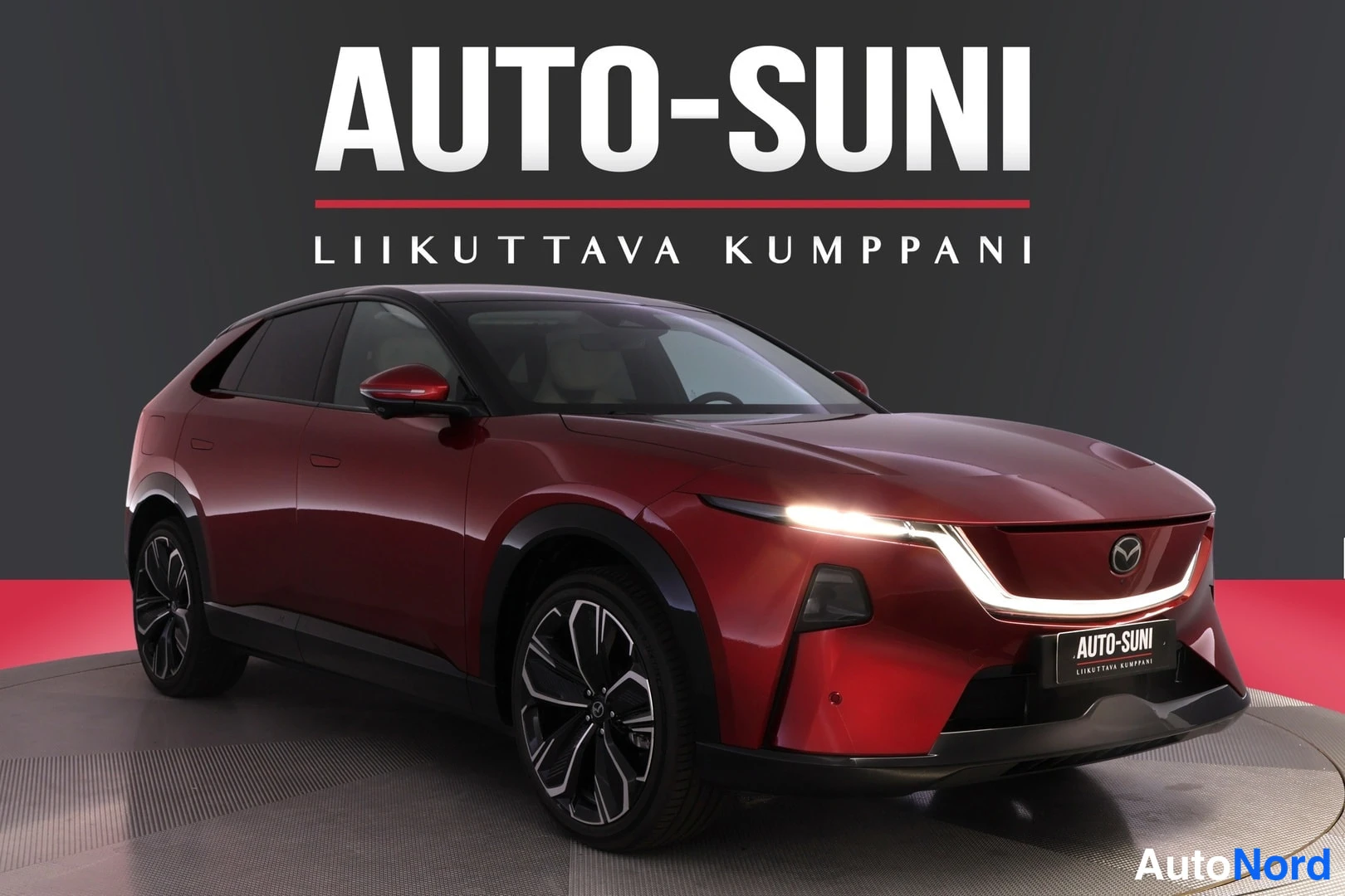 Etuviisto, nokka oikealle: Punainen Mazda CX-60 esikuvassa etuviistosta oikealle,Auto-Suni-logo taustalla.
