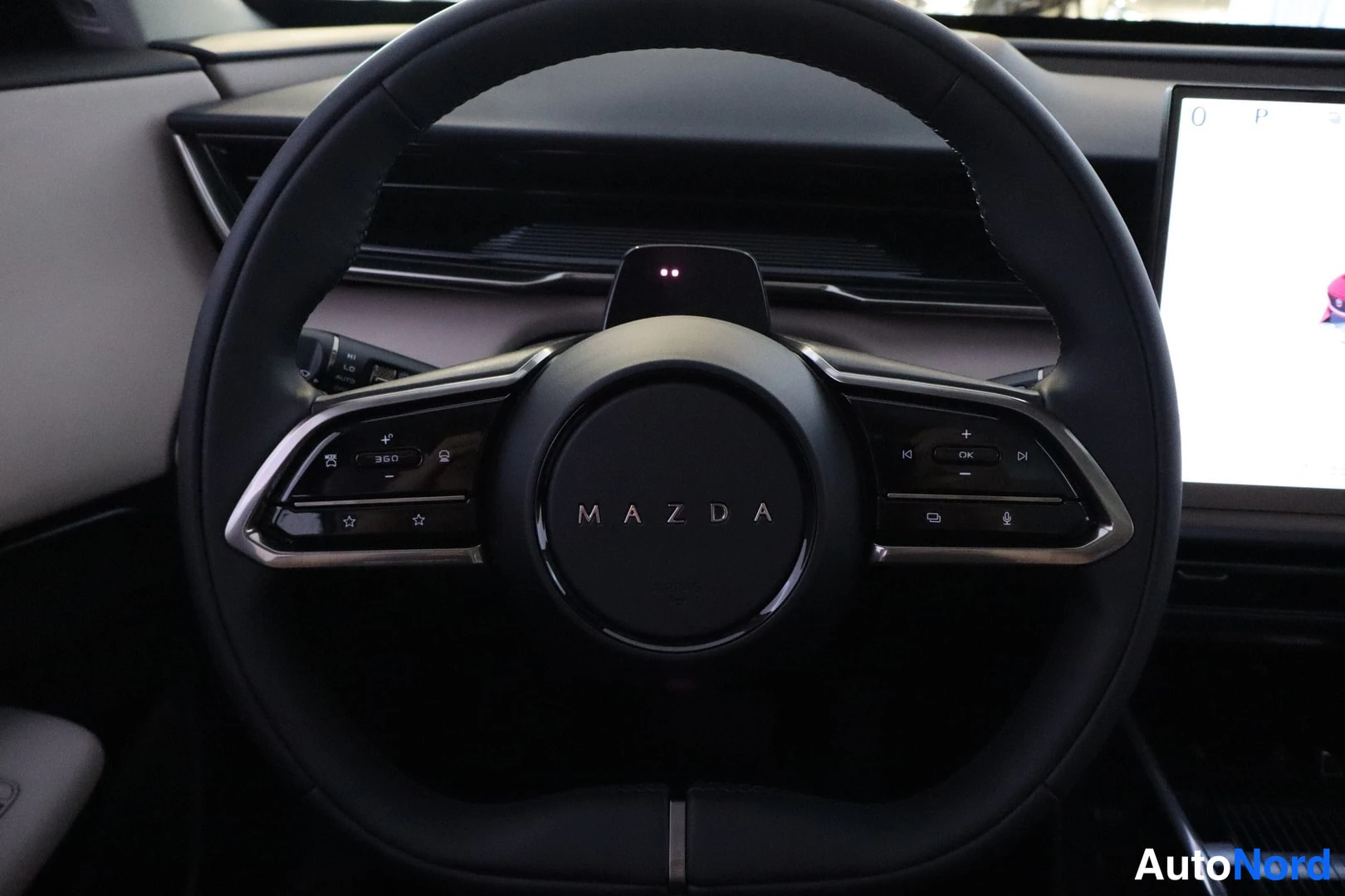 Muu: Mazda-merkillinen ohjauspyörä ja kosketusnäyttö autossa.