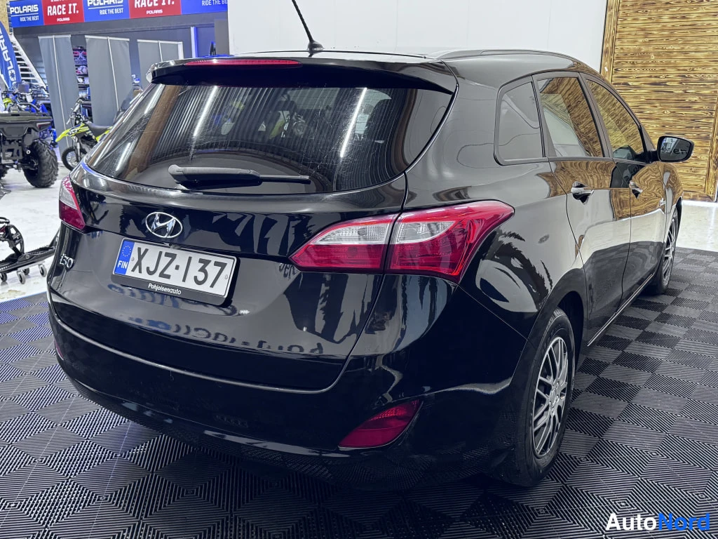 Takaviisto: Mustan Hyundai i30 -auton takanäkymä taustalla moottorikelkkojen ja atv-ajoneuvojen kanssa, rekisterikilpi.