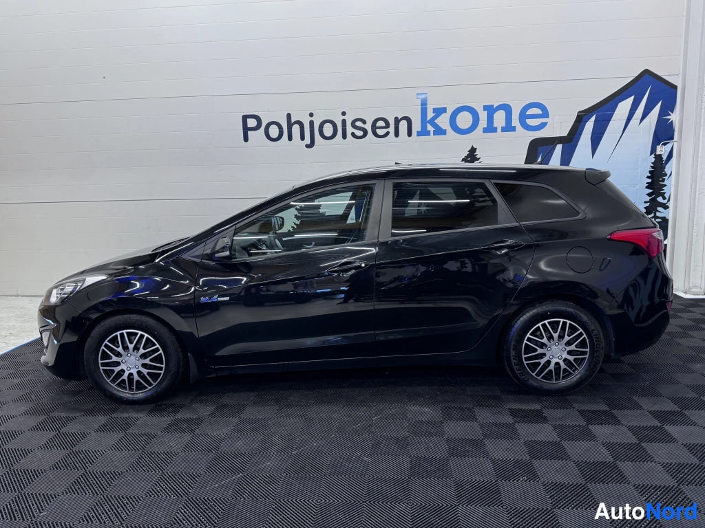 Etuviisto, nokka vasemmalle: Hyundai i30 Wagon, musta, sivukulma sisätiloissa; kevytmetallivanteet ja tummat ikkunat näkyvät.