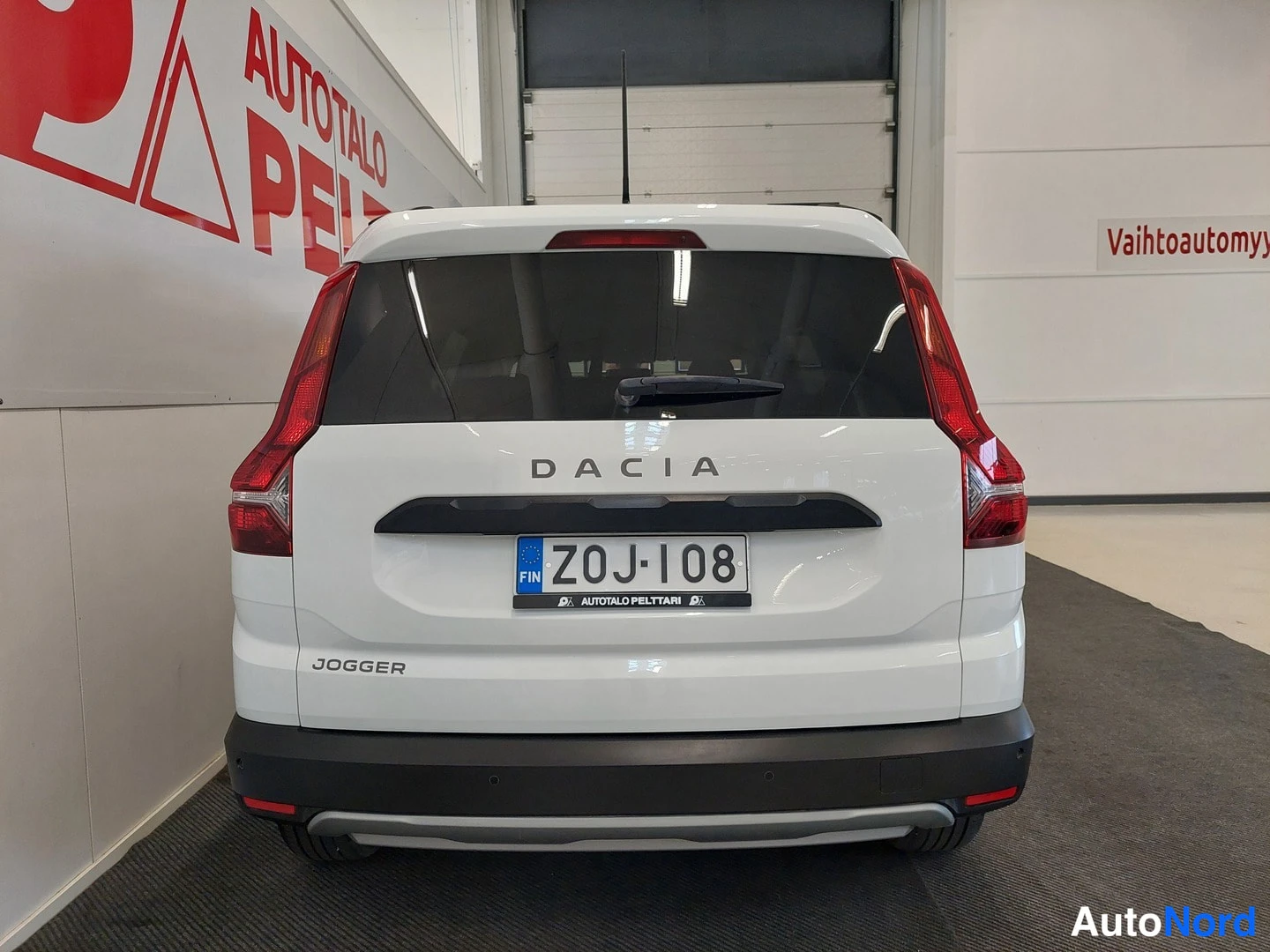 Takaa: Dacia Joggerin takanäkymä: valkoinen koripaneeli, DACIA-teksti ja rekisterikilpi.