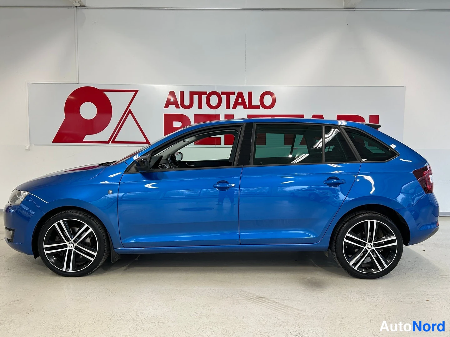 Takaviisto: Sininen Skoda Rapid kyljestä sivulta showroomissa