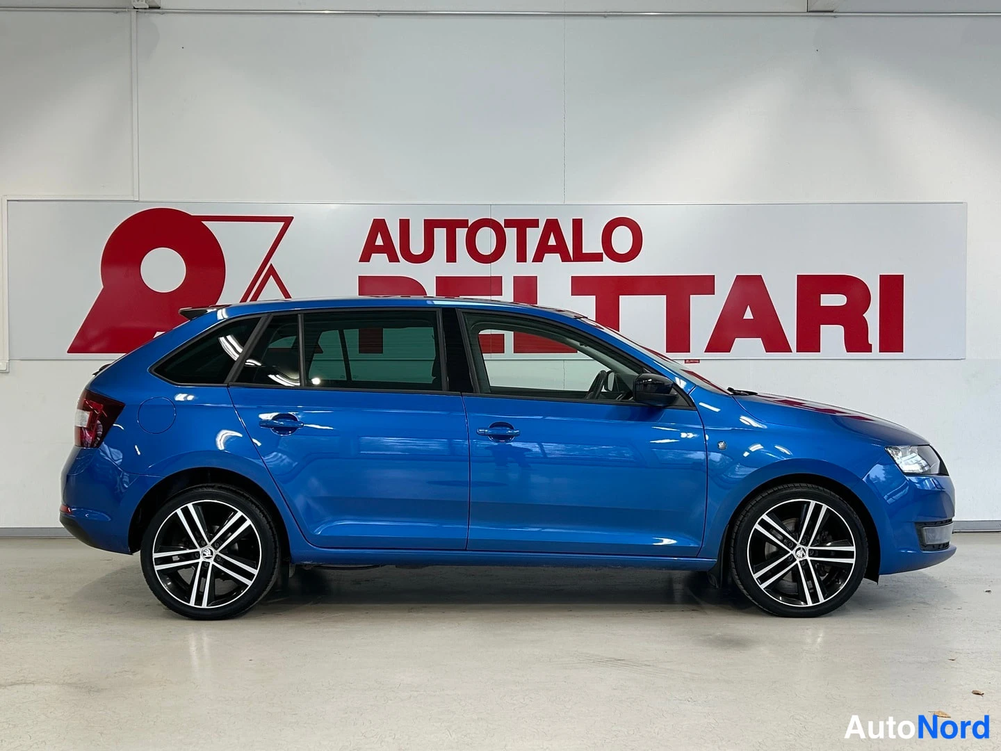 Sivulta: Sininen Skoda Rapid sivulta kuvattuna Autotalo Peltarin tiloissa.