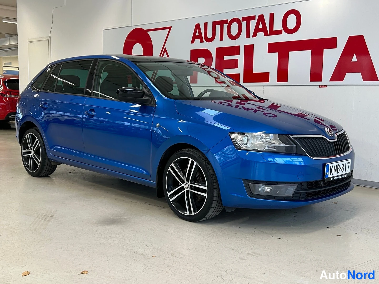 Etuviisto, nokka oikealle: Sininen Skoda Rapid etuviistosta oikealta kuvattuna, rekisterikilpi.
