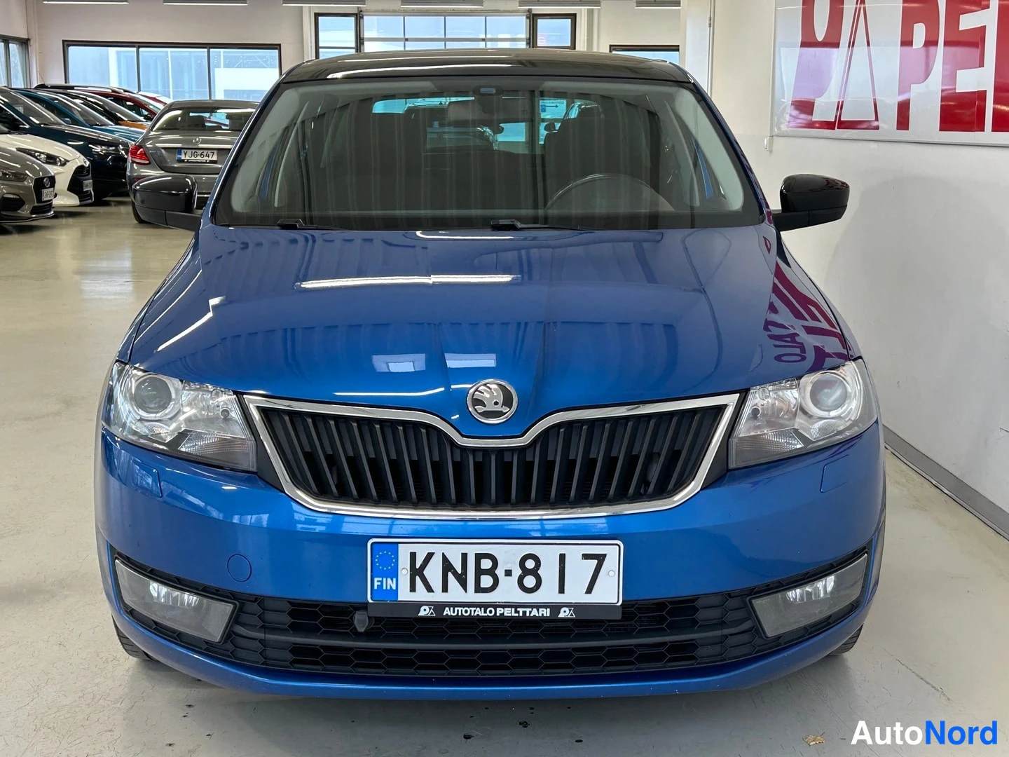 Edestä: Sininen Skoda Rapid suoraan edestä kuvattuna, rekisterikilpi.