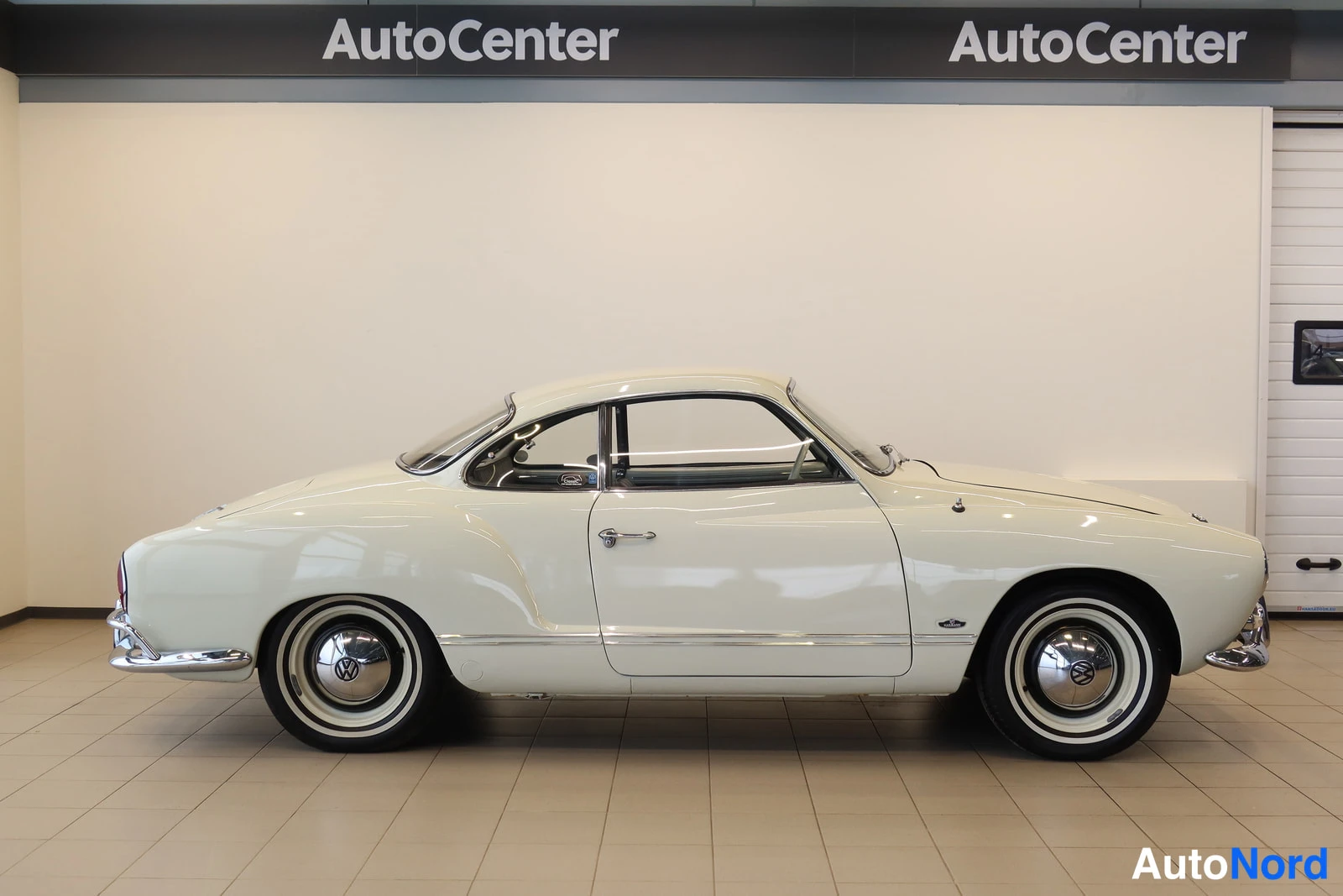 Sivulta: Valkoinen vintage-coupé sivulta kuvattuna AutoCenter-tilassa.