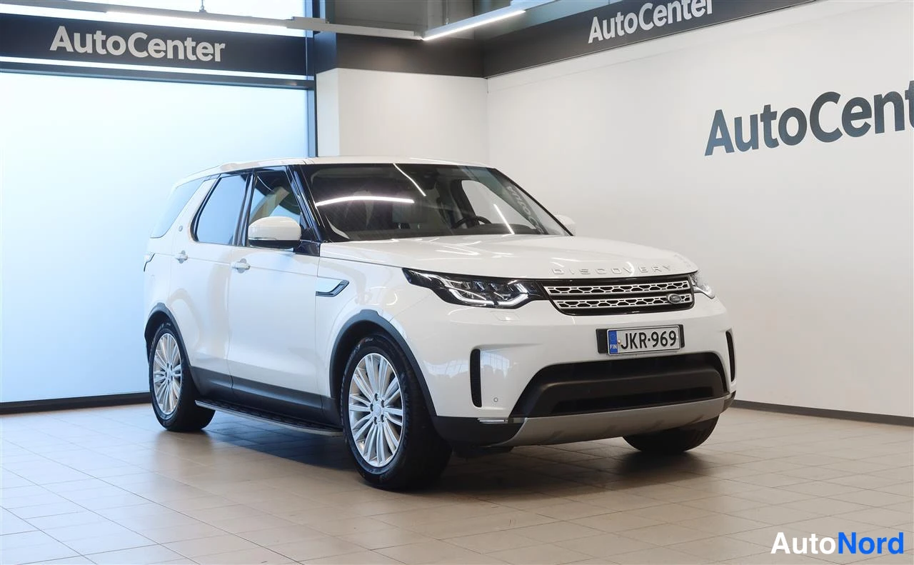 Etuviisto, nokka oikealle: Valkoinen Land Rover Discovery etuviistossa AutoCenter-tilassa, rekisteritunnus.