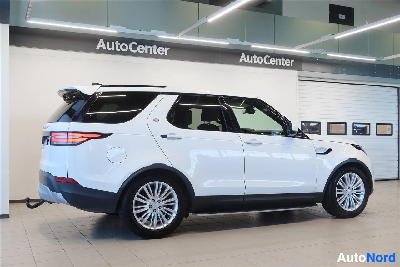 Takaviisto: Valkoinen Land Rover Discovery taka­viistossa AutoCenter-hallissa, takavalo ja sivupaneelit näkyvät.