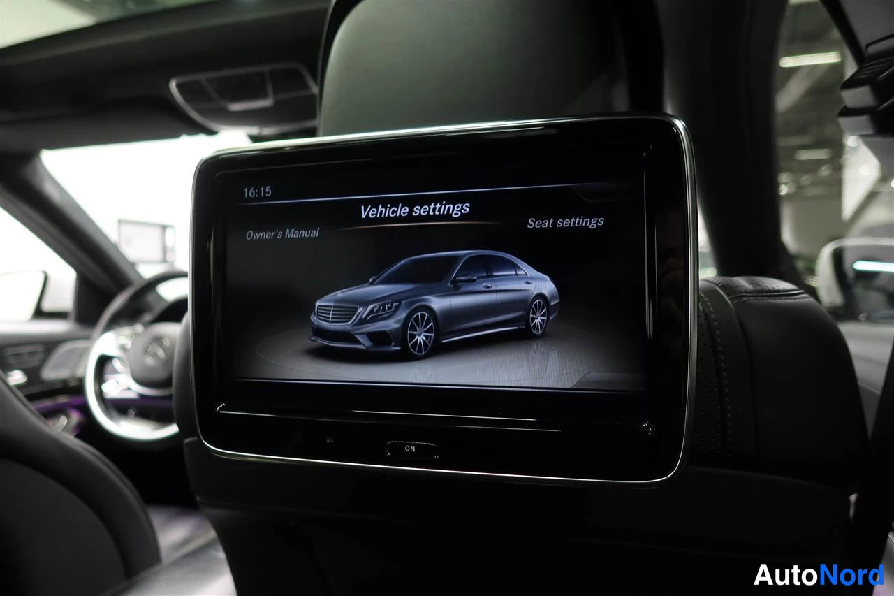 Muu: Auton takaistuimen selkänojaan kiinnitetty näyttö, jossa on auki Vehicle settings -valikko ja ajoissa 16:15 sekä valinnat Owner's Manual ja Seat settings.