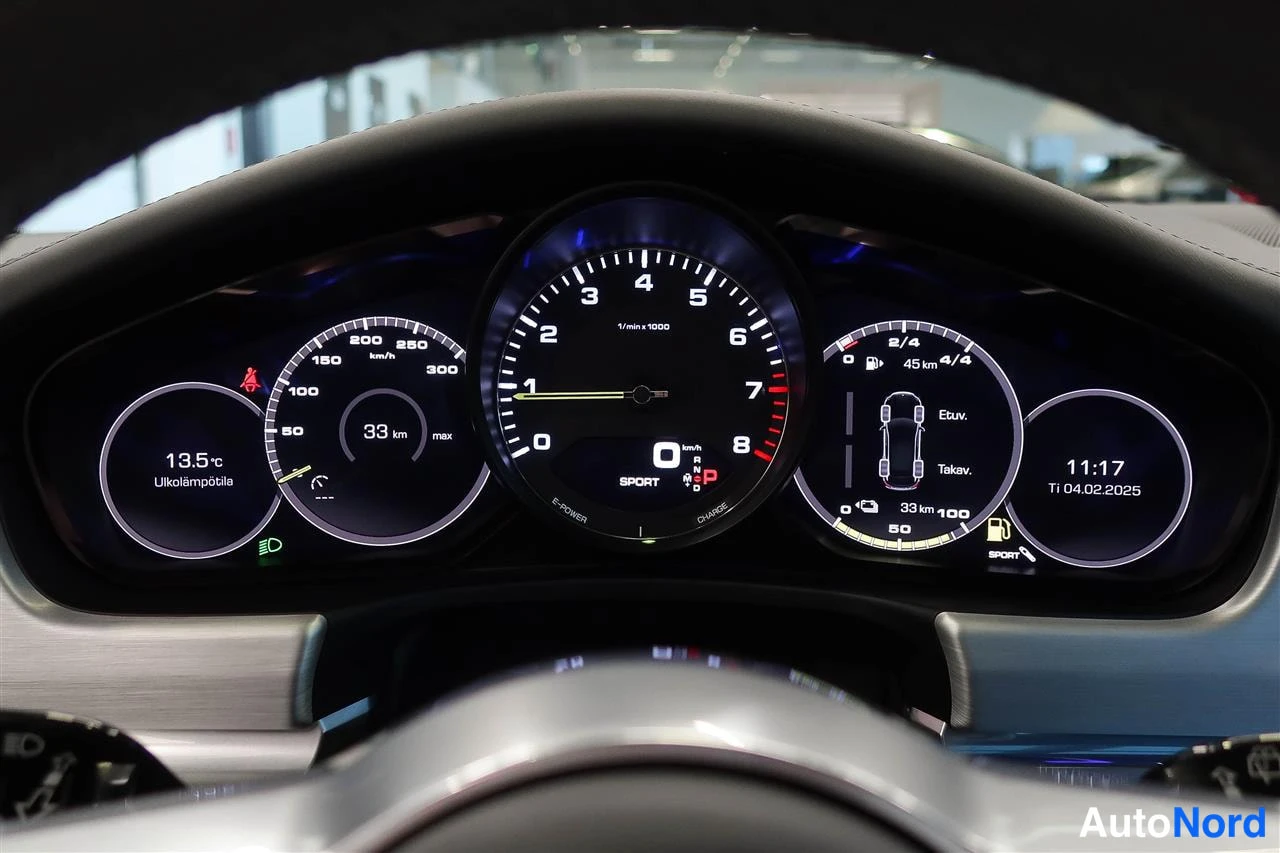 Yksityiskohta: Porsche Panameran mittaristö: hybridi- ja latausnäytöt, nopeusmittari, kierrosmittari ja ulkolämpötila 13,5 °C.