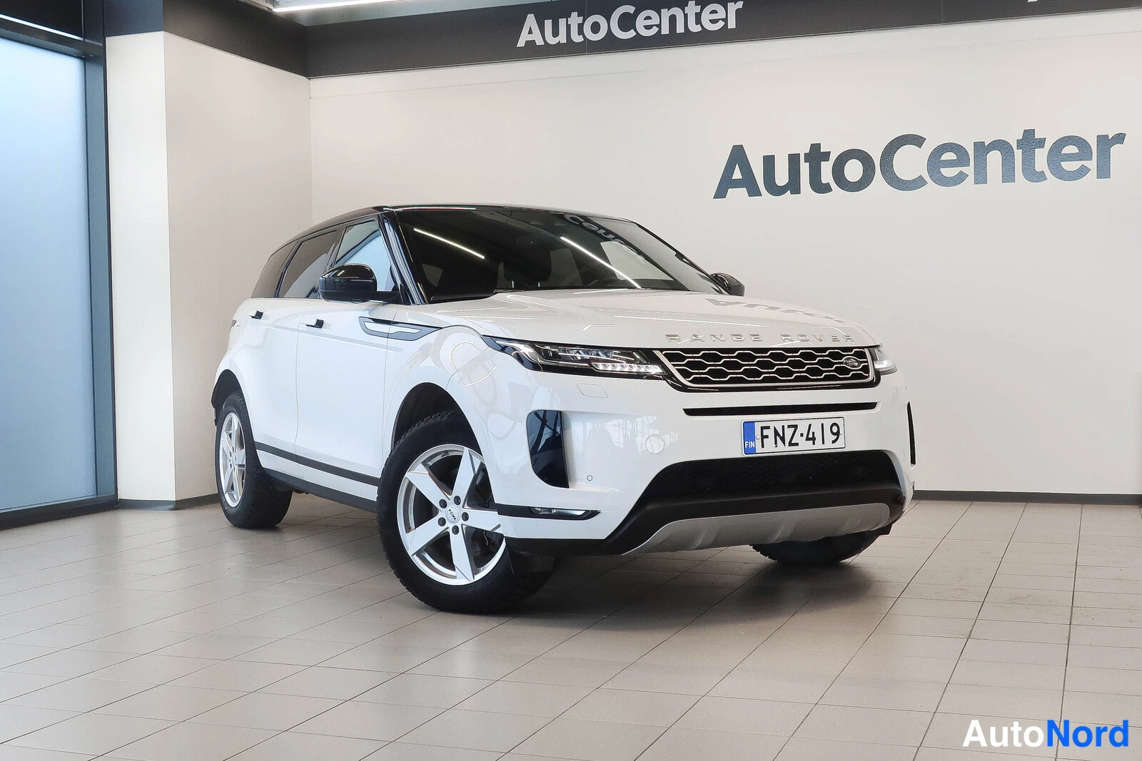 Etuviisto, nokka oikealle: Range Rover Evoque, etukulma vasemmalta, valkoinen auto sisätiloissa.