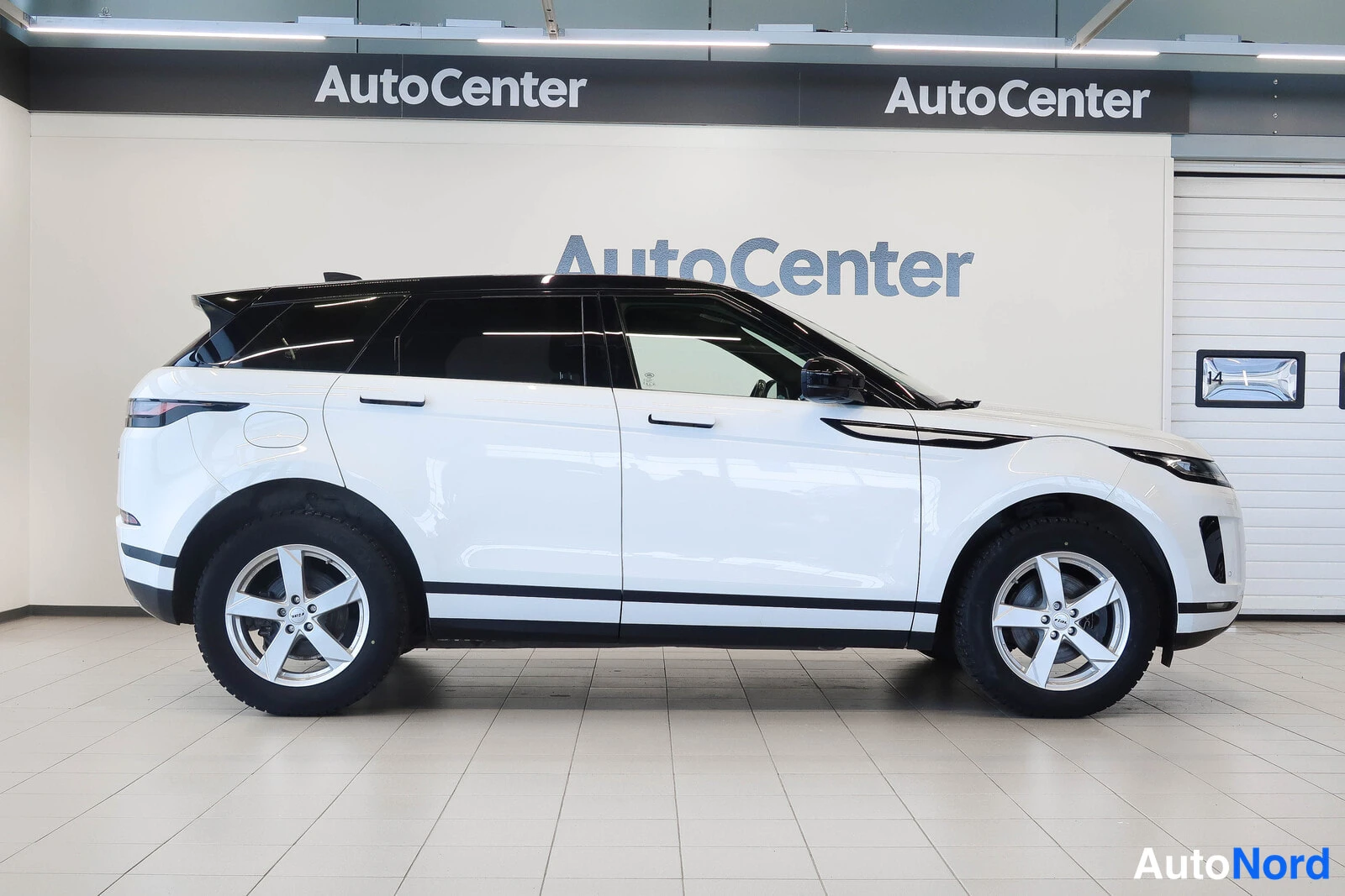 Etuviisto, nokka oikealle: Range Rover Evoque sivulta, valkoinen auto mustalla katolla