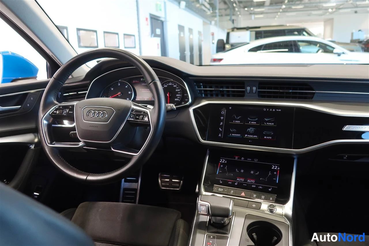 Yksityiskohta: Ohjaamon näkymä: Audi-ohjauspyörä, digitaalinen mittaristo, kaksi kosketusnäyttöä keskikonsolissa.