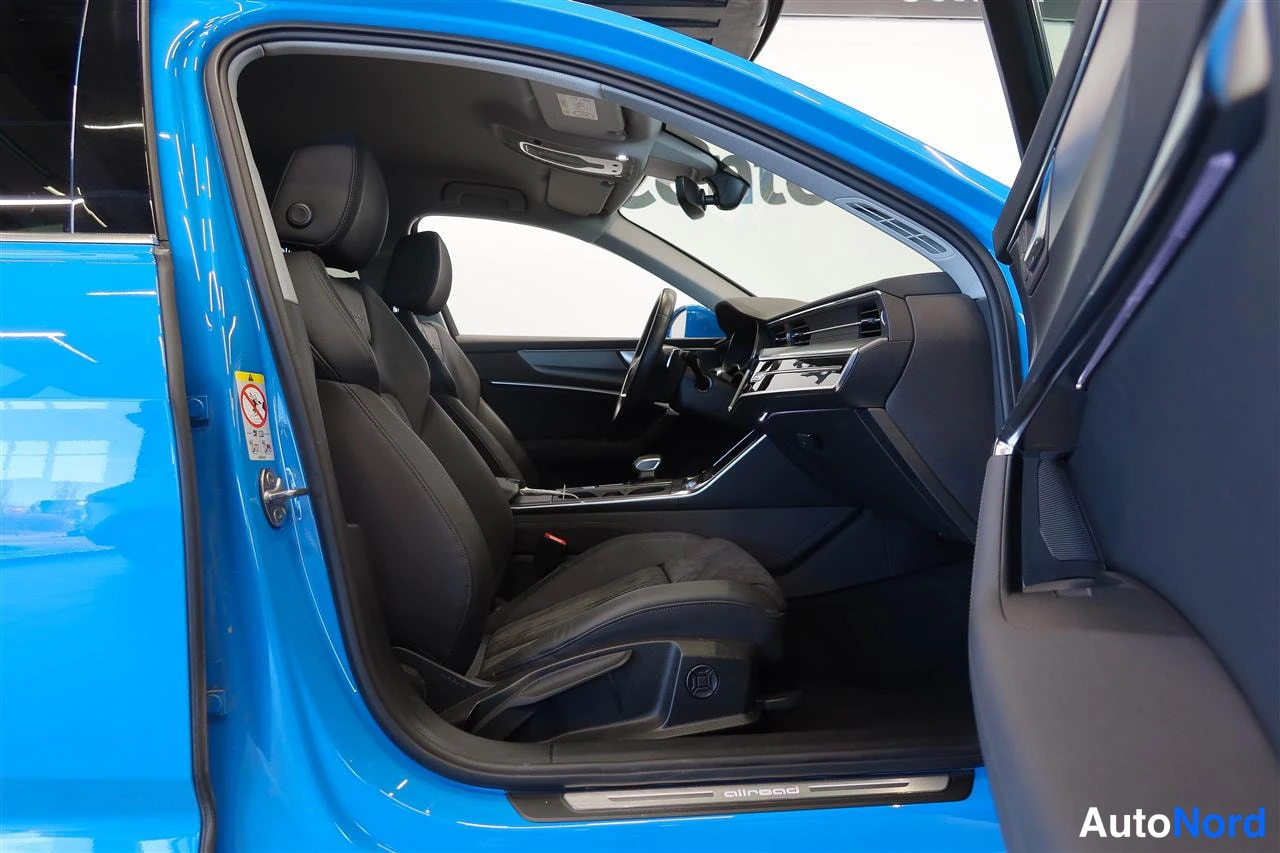 Muu: Auton etupenkkien näkymä avatusta etiovesta: tummat istuimet, ohjauspyörä ja keskconsole, kynnyksellä allroad-teksti.