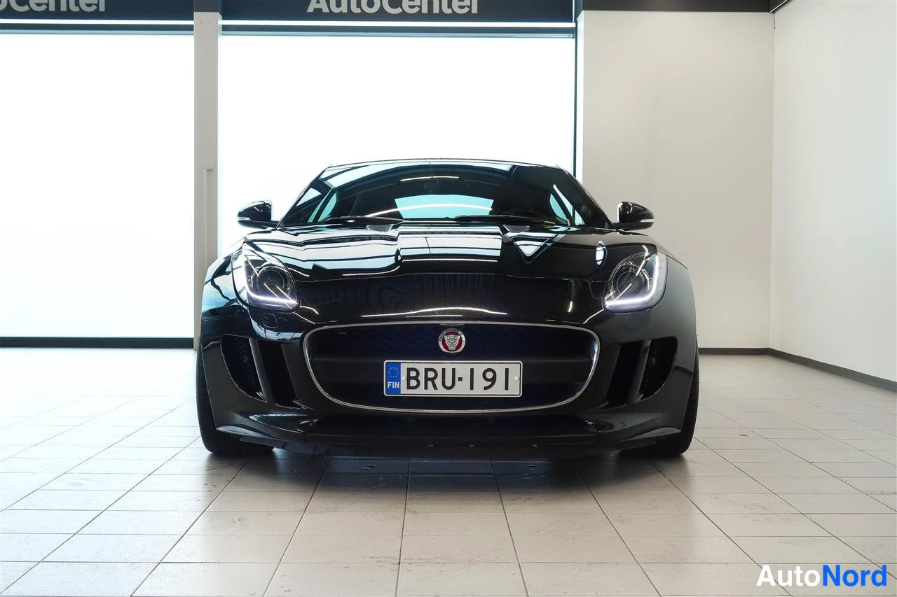 Edestä: Mustan urheilucoupén etunäkymä suoraan edestä, rekisteritunnus, AutoCenter-showroomissa.