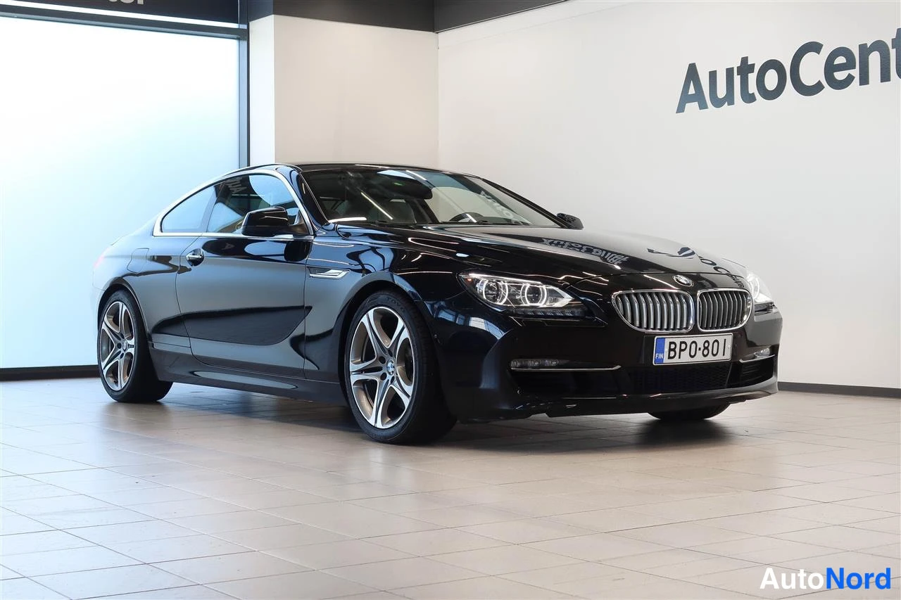 Etuviisto, nokka oikealle: Musta BMW-coupé etuviistossa oikealta, rekisteritunnus BP0-801, showroomissa.