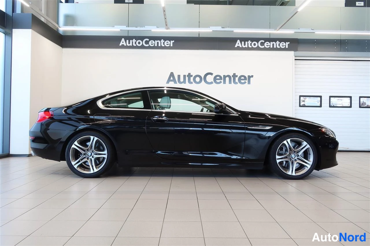 Sivulta: Mustan BMW-coupén sivunäkymä vasemmalta, AutoCenter-showroomissa.