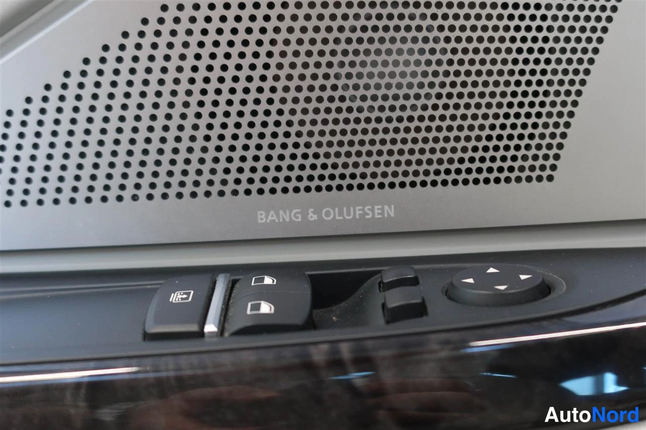 Muu: Oven sisäpaneelin lähikuva: Bang & Olufsen -merkintä kaiuttimen ritilän alla sekä ikkunannostimen ja peilin kytkimet.