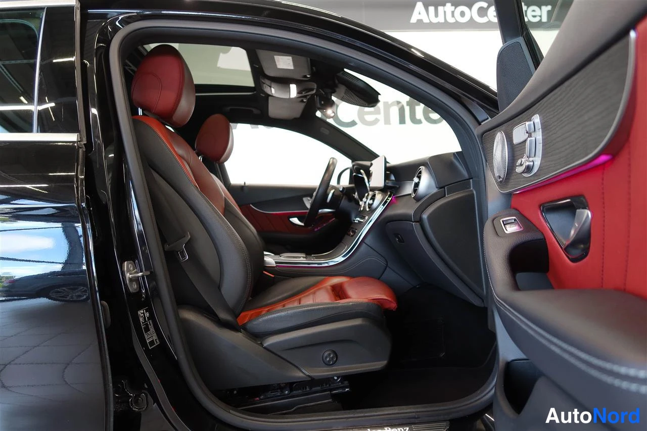 Muu: Avattu kuljettajan oven tako: etupenkin istuin- ja selkänoja on tummaa nahkaa ja punaista nahkaa, kojelauta ja tumma ovi näkyvät taustalla.