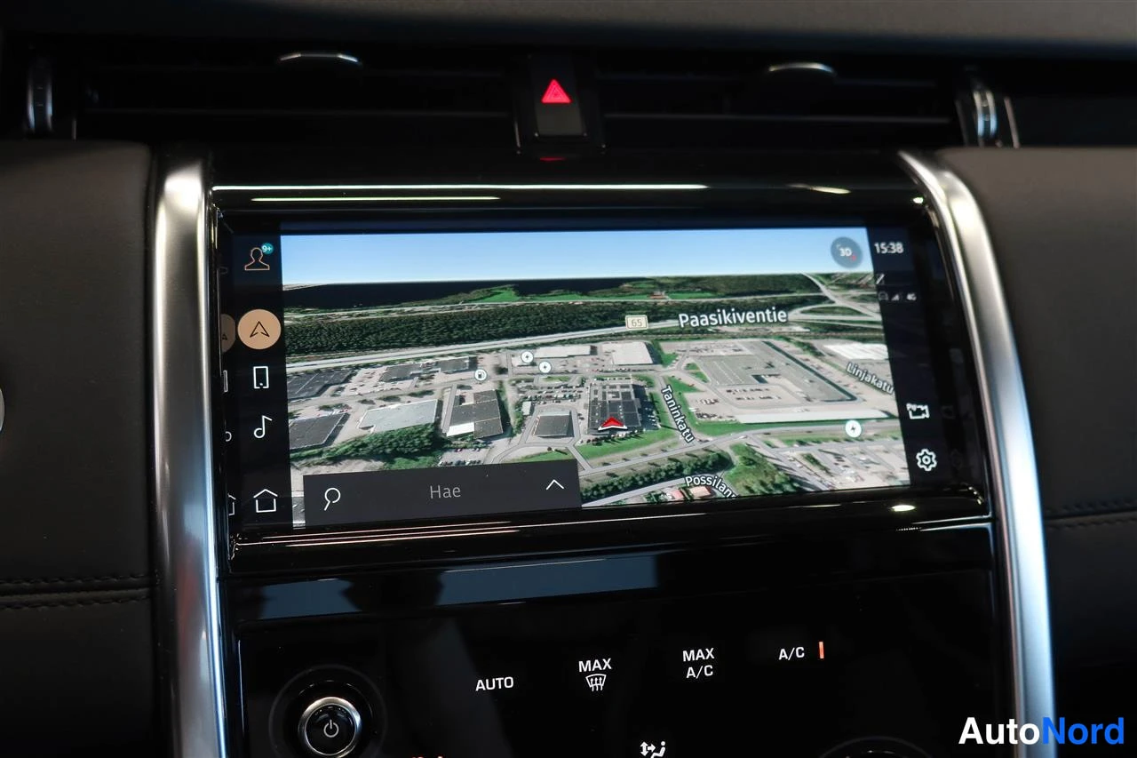 Muu: Auton kojelaudan infotainment-näyttö näyttää 3D-karttanäkymää Paasikiventien alueelta, alla automaattisen ilmastoinnin A/C-painikkeet.