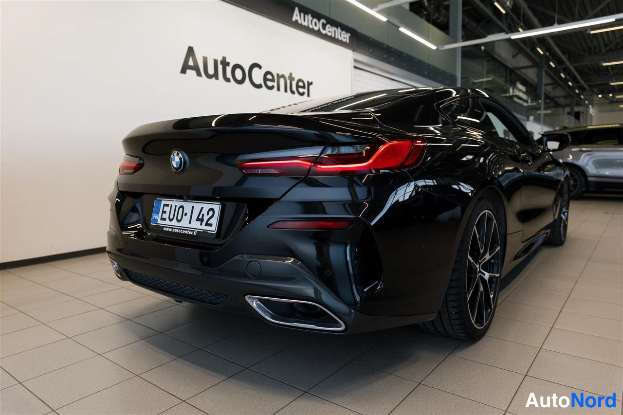 Takaviisto: Musta coupé takaa lähikuvassa AutoCenter-tilassa; BMW-merkki, takavalot, pakoputket ja rekisterikilpi näkyvät.