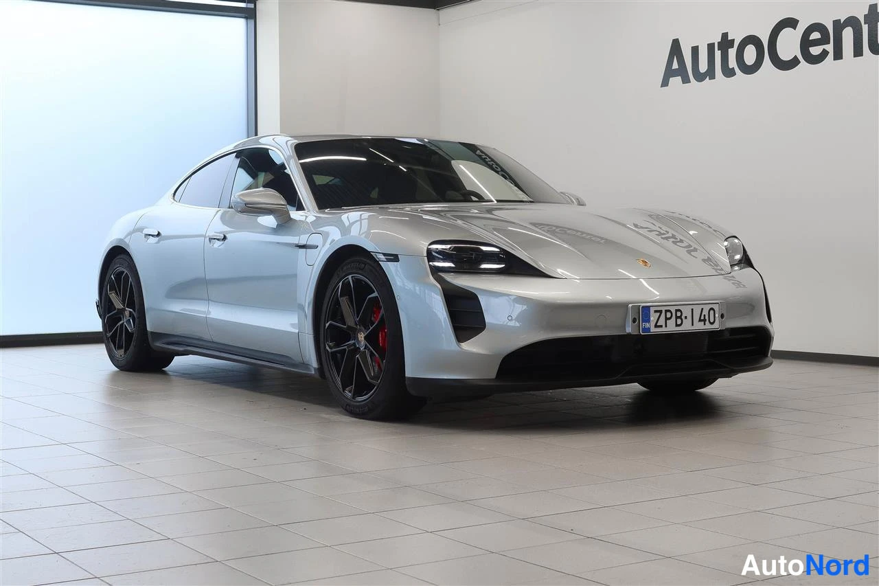 Etuviisto, nokka oikealle: Porsche Taycan 2020, hopeisenä etukulmasta oikealta showroomissa, rekisteritunnus.