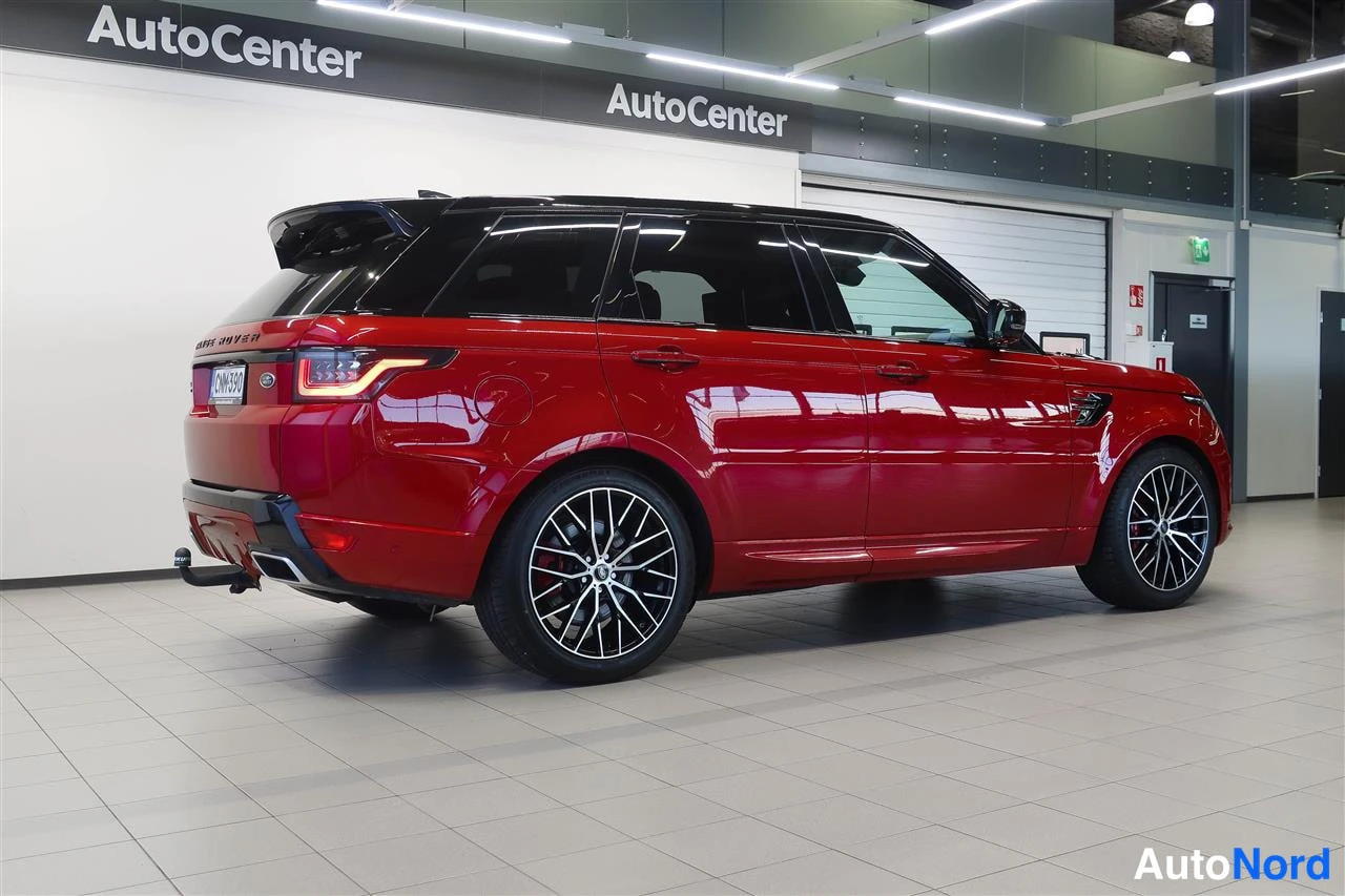 Takaviisto: Land Rover Range Rover Sport 2018, punainen korimuutto takaviistosta; näkyvissä perävaunu, tummat 20-tuumaiset kevytmetallivanteet ja savun­harmaa musta katto.