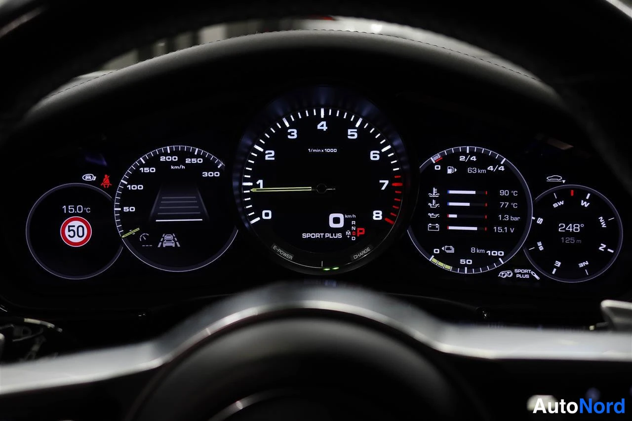 Muu: Porsche Panameran (2018) digitaalinen mittaristo: nopeusmittari, kierrosmittari, polttoainemittari ja ylimääräiset mittarit näkyvät pimeässä ohjaamossa.