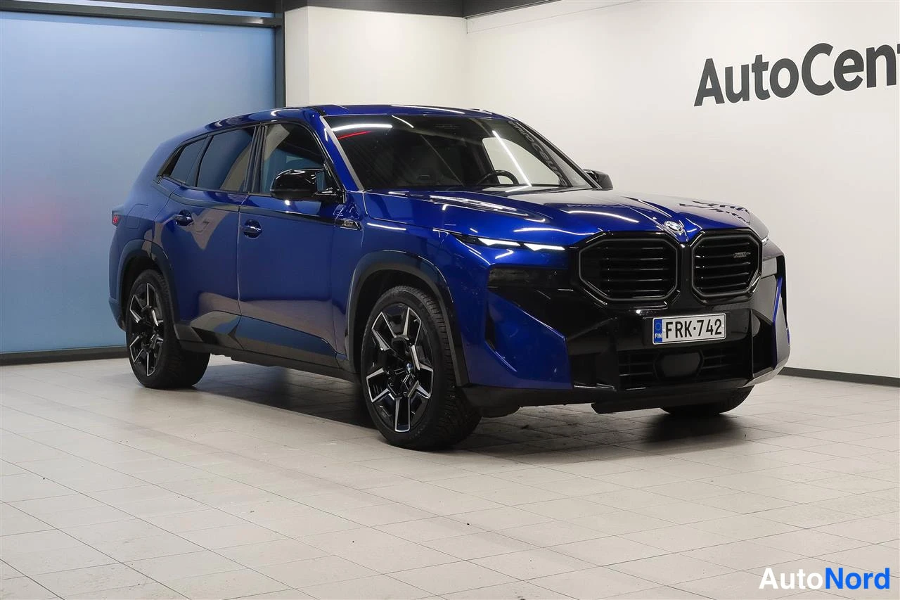 Etuviisto, nokka oikealle: Sininen BMW XM siepaussuunnasta oikealta, kyljenovet ja etusäleikkö näkyvissä, rekisterikilpi.