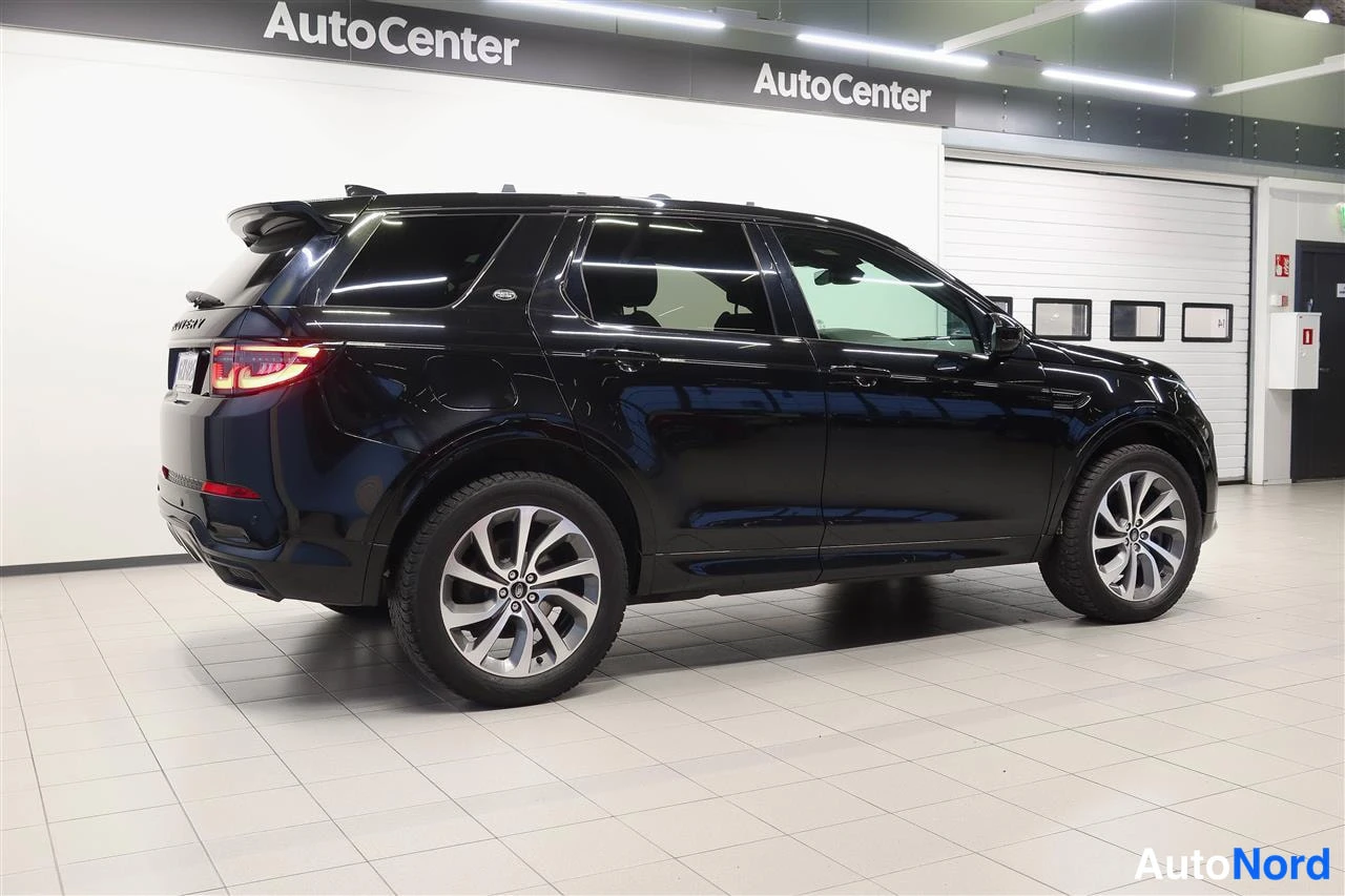 Takaviisto: Kolmivartin takakuva mustasta Land Rover Discovery Sportista vasemmalta, Autocenter-tilassa.