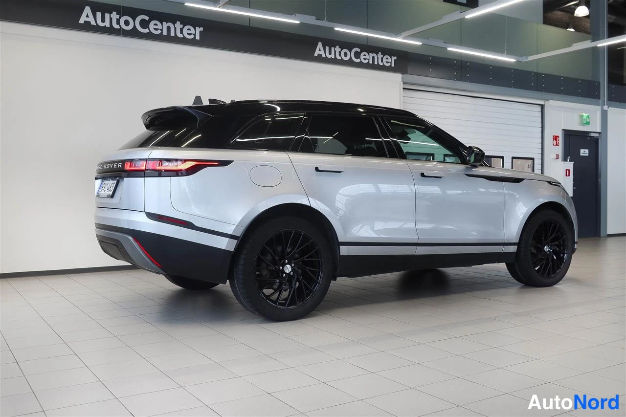 Takaviisto: Hopeanvärinen Land Rover Range Rover Velar takaviistosta sisätiloissa, taustalla AutoCenter-kyltti.