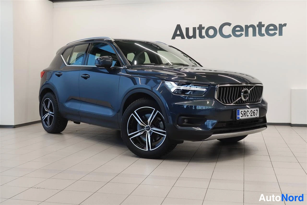 Etuviisto, nokka oikealle: Sinertävänharmaa Volvo XC40 kulmaettäinen myydään etuosan ja oikean kyljen osoittaen sisätiloissa, rekisterikilpi