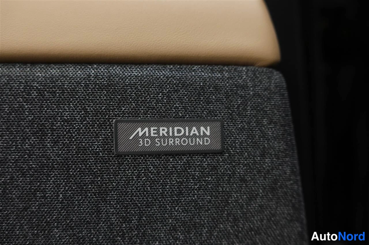 Muu: Meridian 3D Surround -mekaaninen merkki (label) tummassa, tekstiilillä päällystetyssä paneelissa beigen/nahkaisen istuimen alla.