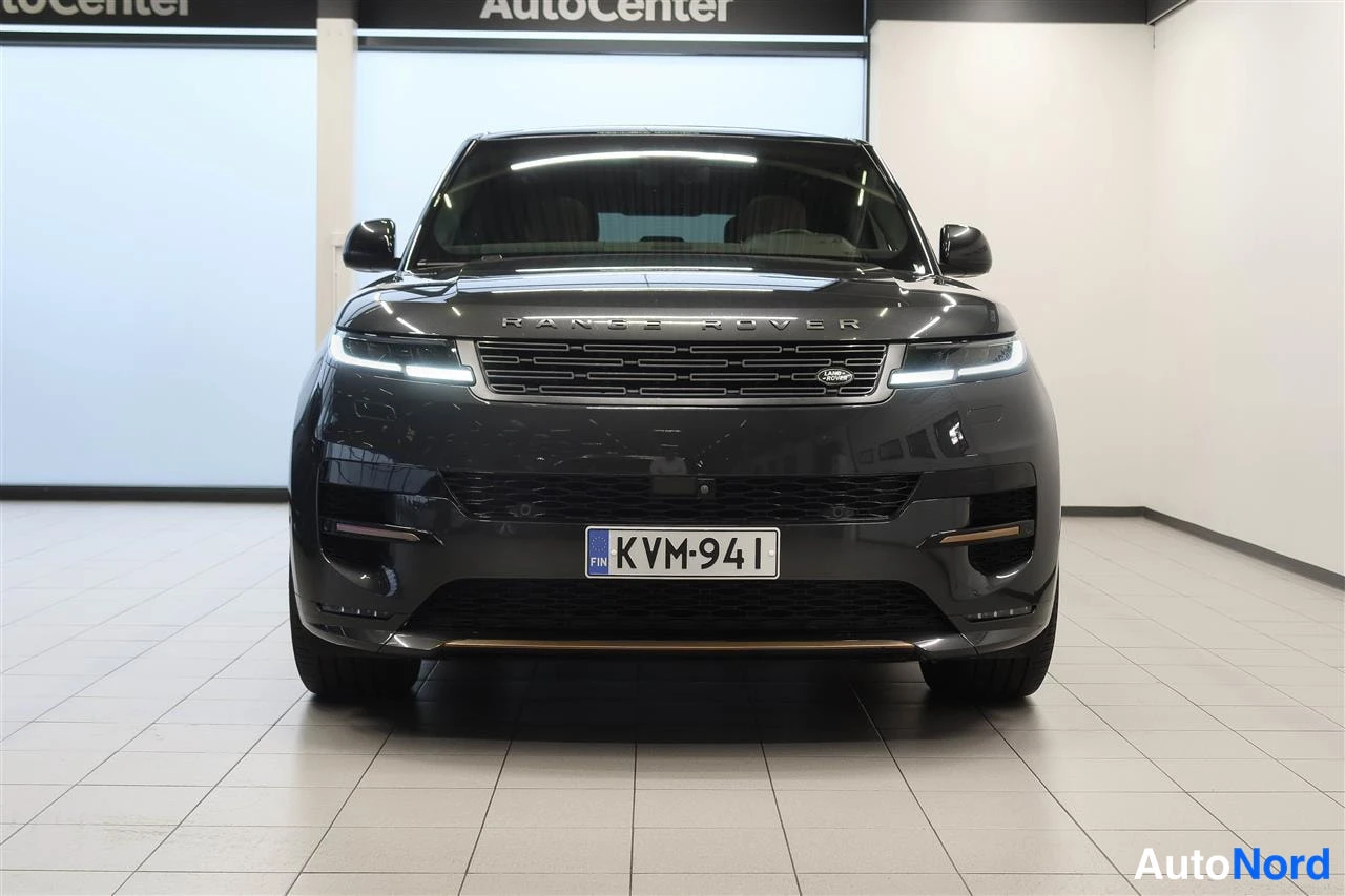 Edestä: Tummanharmaan Range Rover Sportin suora etunäkymä; kyltit RANGE ROVER ja rekisterikilpi.